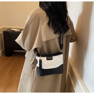 Detail of bicolored quilted shoulder bag with chic FASHION tag and wide strap