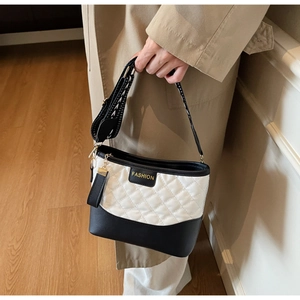 Detail of black and white quilted shoulder bag with wide geometric pattern strap