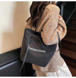 Vue détaillée du grand sac cabas noir en toile montrant l'imprimé lettres et les bretelles