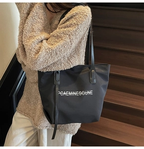 Détail d'un sac cabas noir avec imprimé lettres blanches sur un escalier intérieur