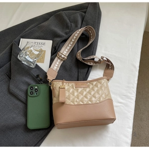 Detail of a quilted patchwork crossbody bag with wide patterned strap and gold fashion tag