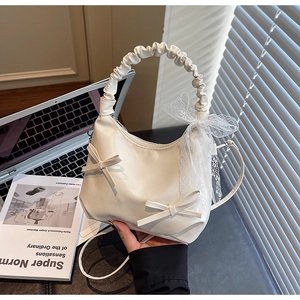 Détail du sac à main blanc avec nœuds et foulard en dentelle sur un bureau moderne