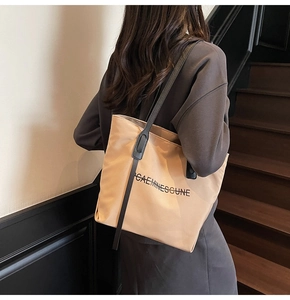 Vue détaillée d'un grand sac fourre-tout en toile kaki avec bandoulière noire et motif
