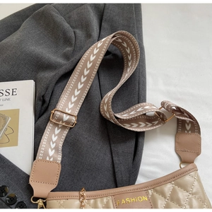 Close-up of beige quilted bag with FASHION logo and patterned wide fabric shoulder strap