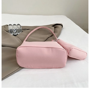 Detailed shot of pink nylon handbag with mini accessory pouch on white fabric background