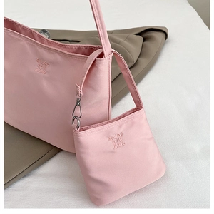 Close-up of pink nylon shoulder bag featuring embroidered letters and matching coin pouch