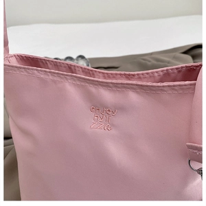 Close-up of pink nylon shoulder bag featuring detailed tone-on-tone 3D embroidery
