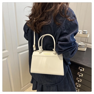 Detail view of cream leather tote bag with yellow Fashion Bag text and shoulder strap
