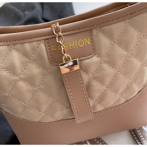 Detailed close-up of beige quilted handbag with gold chain accent and fashion buckle