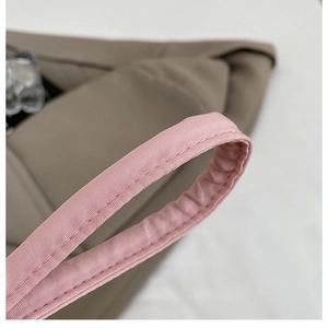 Detailed close-up of pink strap stitching and twill texture on a brown shoulder bag