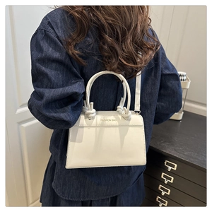 Detail of white tote bag featuring unique knot handles and gold Fashion Bag lettering
