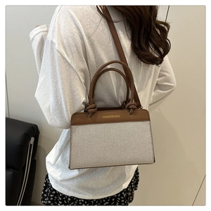 Détail d'un sac bandoulière bicolore avec poignée nouée et lettrage tendance