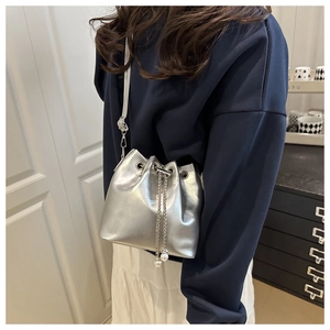 Detail of silver oil wax leather bucket bag with metallic luster and pearl chain straps