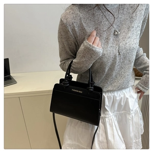 Close-up of black leather crossbody bag with gold Fashion Bag logo and slim strap