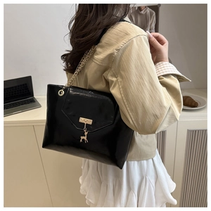 Close-up of a glossy black crossbody bag with gold chain strap and deer charm detail