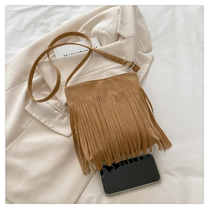 Detailed view of a brown suede crossbody bag featuring long fringes and silver buckle