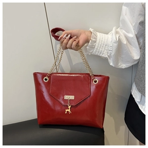 Detail of red glossy leather tote with golden chain strap and deer charm accessory