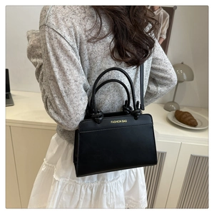 Détail du sac bandoulière noir avec texte doré FASHION BAG et poignée de texture tissée