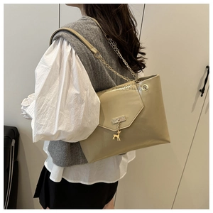Détail du sac bandoulière en cuir beige avec chaîne dorée et pendentif cerf élégant