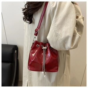 Close-up of red oil wax leather bucket bag featuring silver chain and pearl details