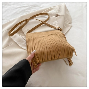 Close-up of bohemian khaki suede crossbody bag featuring long stylish tassels and strap