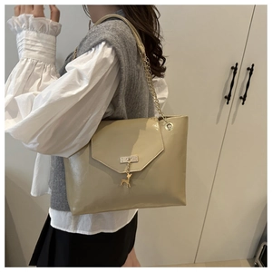 Close-up of khaki tote bag featuring gold deer charm and chain leather shoulder strap