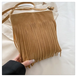 Detail of caramel suede crossbody bag featuring long fringe tassels and adjustable strap