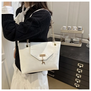 Detail of white PU leather tote bag with gold chain strap and deer charm on a model