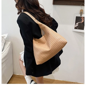 Close-up of light brown woven hobo shoulder bag showing intricate leather texture and pattern