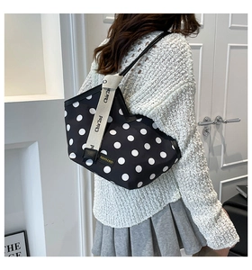 Detail of polka dot tote bag with wide beige strap and decorative brand label