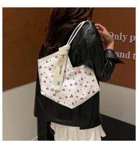 Detail of white canvas tote bag with cherry print and chic knotted branded shoulder strap