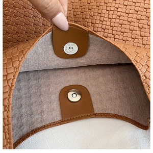 Close-up of secure silver magnetic buckle on a brown woven texture tote bag