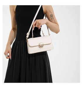 Detailed close-up of cream-white flap bag with elegant gold buckle and adjustable strap