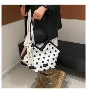 Detail of white leather tote bag with black polka dots and stylish wide fabric shoulder strap