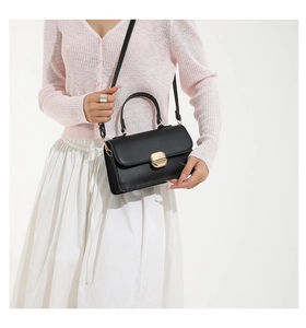 Detail of elegant black leather handbag with premium gold hardware lock and shoulder strap