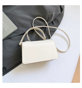 Detail shot of a white rectangular PU leather handbag with gold metal hardware and strap
