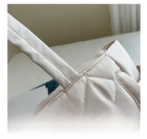Close-up of diamond quilted stitching and reinforced handle on cream tote bag