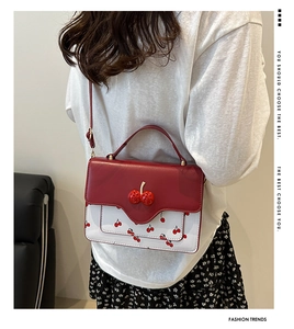 Detail view of cherry crossbody bag with red floral pattern and 3D cherry decor
