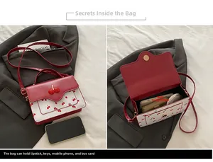 Detail of red and white cherry crossbody bag interior showing phone and lipstick storage