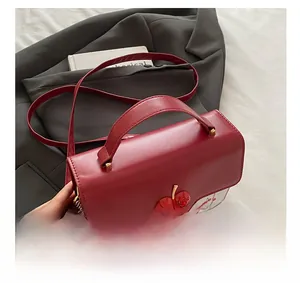 Close-up of red and white leather crossbody bag with cherry prints and hanging charm