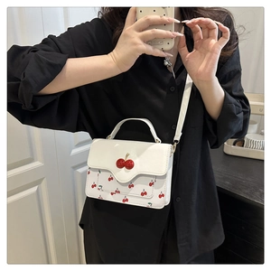 Detail of cute cherry print crossbody bag with scalloped flap and 3D cherry buckle