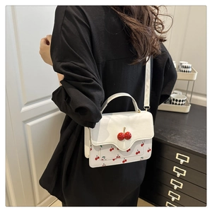 Detailed back view of a white handbag with cherry patterns and a 3D cherry buckle detail