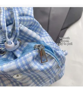 Close-up of smooth metal zipper and blue plaid fabric detail on the drawstring backpack