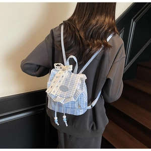 Vista posteriore di una modella con lo zaino a quadretti blu con pizzo e fiocco chic