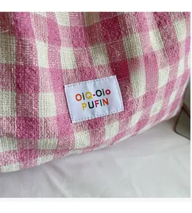 Detail of pink and white checkered woven shoulder bag with embroidered brand label