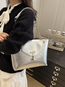 Silver metallic tote bag with chain strap and deer charm shown on a female model
