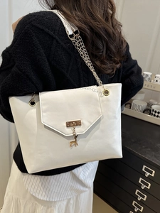 Elegant white leather tote bag with gold chain strap and deer pendant shown on shoulder