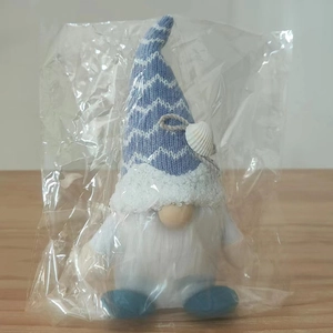 Detail of nautical summer gnome plush with blue striped knit hat and shell decoration