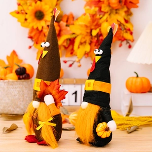 Detail von Erntedank-Zwergen mit Ahornblatt und Kürbis vor herbstlichem Hintergrund