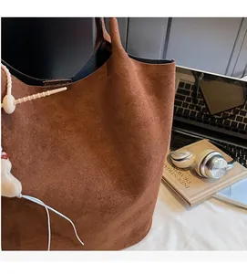 Close-up of vintage brown suede tote bag featuring smooth stitching and white charm accessory